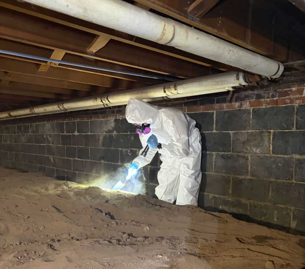 Efficient asbestos abatement in crawl space using protective gear and advanced equipment.